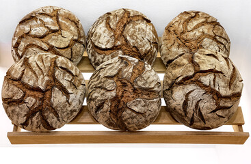 Round loaves of dark rye bread on shelf in bakery. Big round bread isolated on white background.