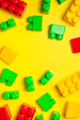 Naklejka premium Children's plastic multi-colored constructor on yellow background, top view. Game for children, toddlers, building blocks, bricks, toys, child development, co-creation. Flat lay