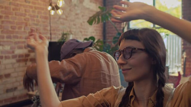 Slow motion portrait of cheerful young female squatter enjoying dancing to music with her friends