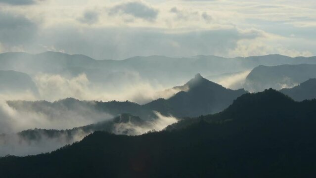 tme-lapse, of mountains top view with flowing/flying clouds and fogs in the morning sunrise.