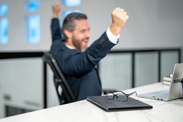 Office workplace. Handsome business man working with laptop at desk in office. Businessman typing on keyboard, business meeting. Excited Businessman working in office. Office worker using laptop.