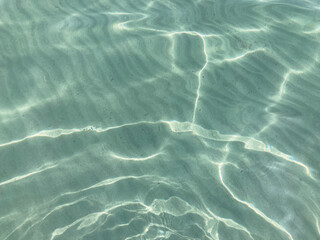 Light blue turquoise, clear and transparent sea water with sun glares