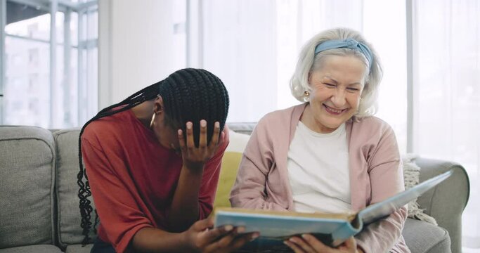 Photo album, assisted living and a happy senior with her black woman caregiver on a sofa in the living room. Smile, funny and elderly resident laughing at a memory with a nurse in a retirement home