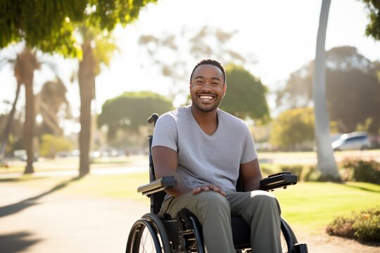 Smiling Young African American Man In A Wheelchair Enjoying The Autumnal City Park.