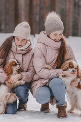 Happy young caucasian family plays with dogs in winter in a pine forest. The concept of Christmas and New Year