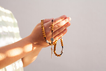 Praying hands with rosary. Children's hands on white wall.