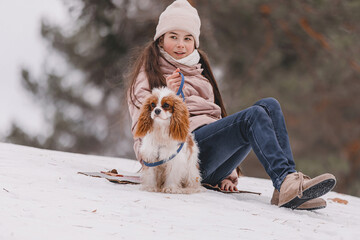 Cute girl playing with dog on the winter park, forest. The concept of Christmas and New Year