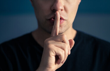 Secret and silence. Quiet silent shh gesture with finger on lips. Man doing expression with hand on mouth. Taboo topic, censorship or freedom or speech. Conspiracy theory. Confidential talk. - obrazy, fototapety, plakaty