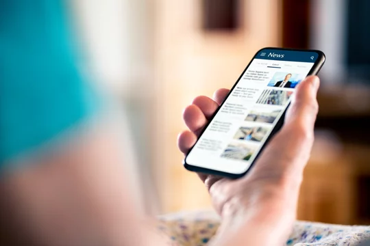 News online. Mobile phone screen. Senior woman reading newspaper on web portal and website. Latest daily information. Headlines on internet. Old person with smartphone. Misinformation, disinformation.