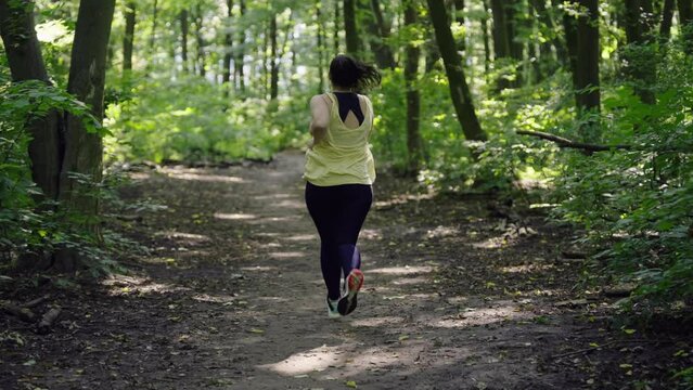 Embracing Fitness and Health: Plus-Size Girl Running in the Enchanting Forest Weight Loss and Active Lifestyle Concep. High quality 4k footage