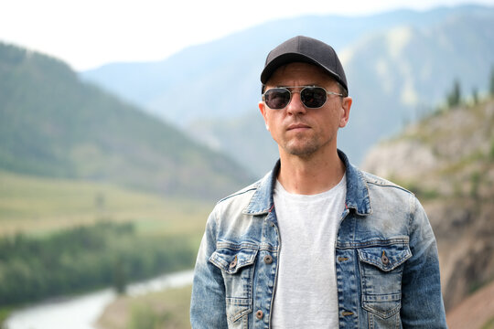 Photo of a male traveler in the mountains close-up. Man is in sun glasses