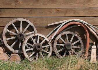 Fototapeta na wymiar Old, wooden wheels for a cart or wagon near the barn wall. Near the rocker. Russian village.