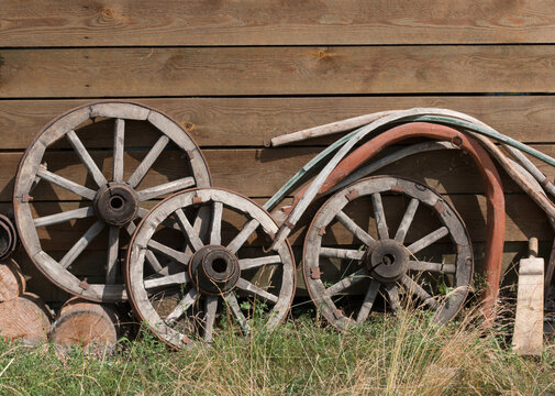 Old, wooden wheels for a cart or wagon near the barn wall. Near the rocker. Russian village.