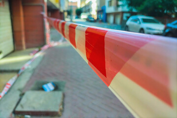 Red and white restrictive tape on the street, stretched to restrict access to this area of the...