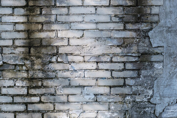 Brick wall with traces of moisture and cracked, peeling plaster