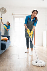 Asia young woman in maid uniform cleaning kitchen floor with wet mop at home  - obrazy, fototapety, plakaty