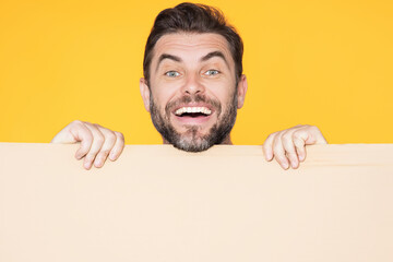 Happy man holds the sign, blank card. Placard ready for your product. Sign to your text. Smiling man showing blank sign board over studio isolated background. Empty blank board. Area for advertising.