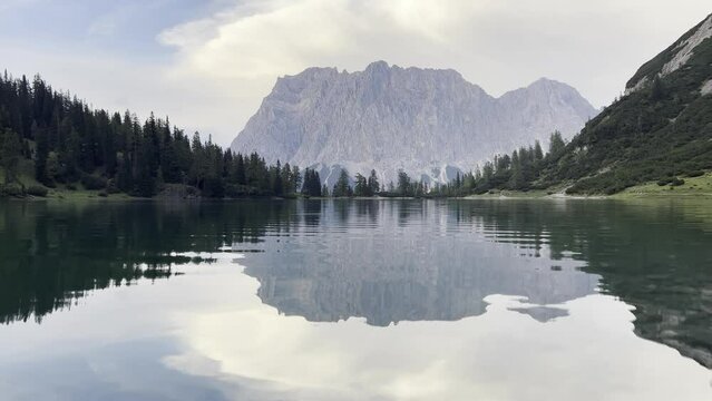 Mountain Zugspritze is reflected on lake Seebensee sky light overcast