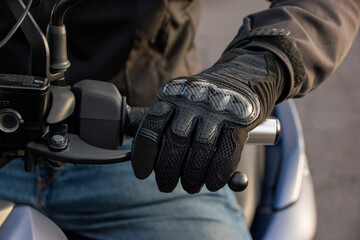 Fototapeta premium Close-up of a gloved biker's hand pulling the brake of his motorcycle. Road safety concept.