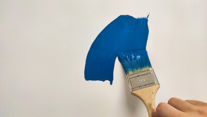brush with blue paint on a white wall