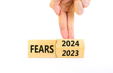 2024 fears new year symbol. Businessman turns a wooden cube and changes words Fears 2023 to Fears 2024. Beautiful white background, copy space. Business 2024 fears new year concept.