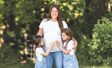 Pregnant woman posing in the parkwith her two childs