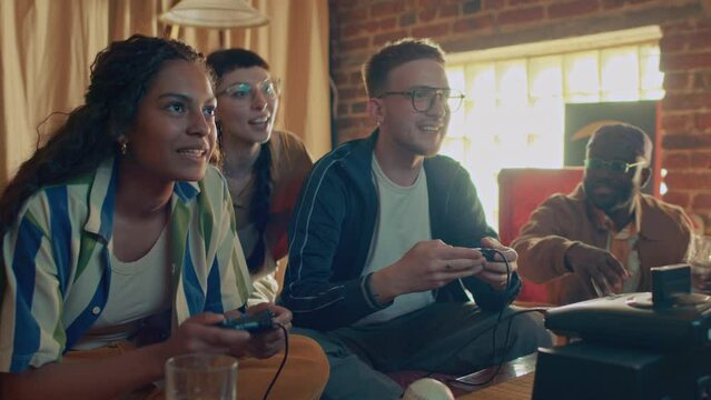 Group of ethnically diverse friends enjoying playing retro console game, Caucasian guy winning it