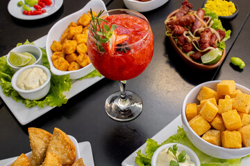 Drink Caip Morango em mesa com petiscos e comidas de boteco