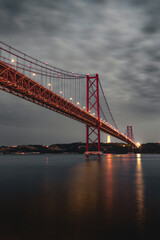 Fototapeta na wymiar Vertical image of the 25 April bridge (Ponte 25 de Abril) located in Lisbon, Portugal, crossing the Targus river at night.