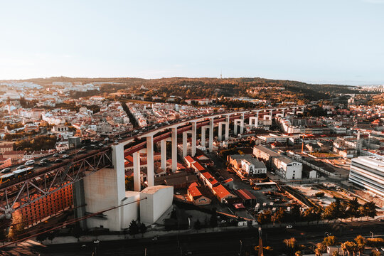 Aerial horizontal photo of streets and buildings of Lisbon on sunset. The Bridge of 25 april in Libson with historic city centre and rooftops from above on golden hour - taken by drone.