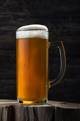 A mug of beer stands on an old wooden background