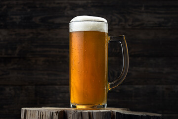 A mug of beer stands on an old wooden background