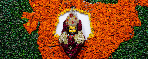 a face sculpture of khatu shyam decorated with lots of flowers and leaves