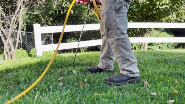A low angle view of an exterminator injecting termite treatment in the backyard of a home.  	
