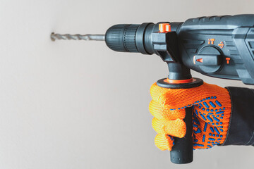 Hand in protective gloves with hammer drill, perforator