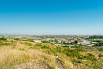 Fototapeta premium Panorama. Daytime landscape of the surroundings of the ancient city of Perge from a high point. Agricultural fields near the city of Perge in the province of Antalya, Türkiye.