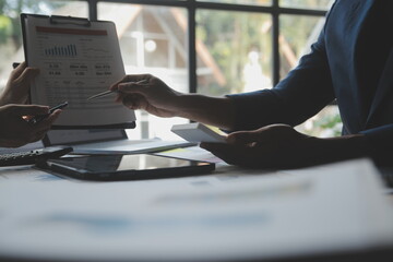 Financial analysts analyze business financial reports on a digital tablet planning investment project during a discussion at a meeting of corporate showing the results of their successful teamwork.
