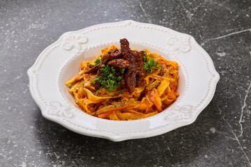 Pasta with beef in whitebowl. Grey background. Close up. Top view.