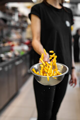 woman chef preparing french fries in restaurant kitchen