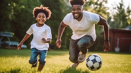 African American father and his son energetically playing football in the backyard.