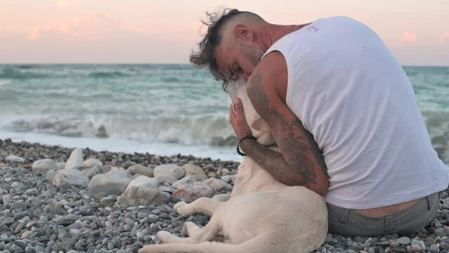 a kind guy with a puppy dog sitting on the seashore friends are cute