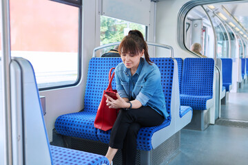 Naklejka na ściany i meble Woman is a passenger inside an electric train car