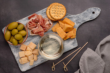 Food photography of antipasto, white wine, cheese, ham, serrano, olive, prosciutto, cracker,...