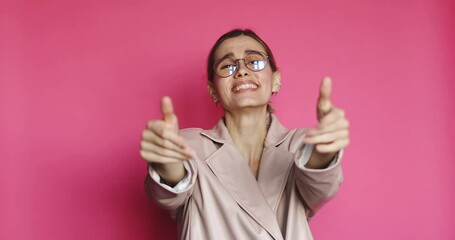 Come here, follow me! Beautiful young woman low tail hairstyle in jacket, pointing to you, making beckoning gesture with hands, inviting to approach, looking playful flirting on pink background.