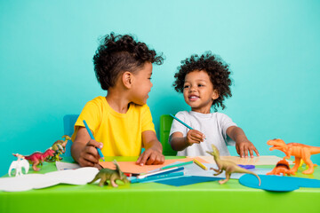 Full length photo of charming schoolboys sit table have fun studying best friends dressed stylish garment isolated on cyan color background