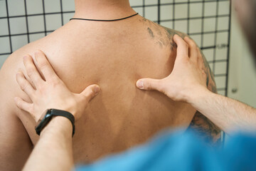 Physical therapist performing thoracic spine palpation in adult person