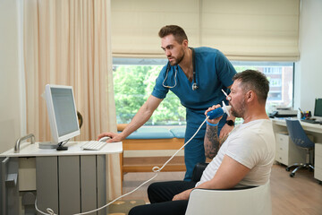 Adult man taking spirometry test in presence of doctor