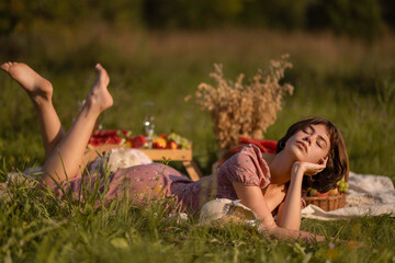 Portrait of a girl in a light pink dress on a summer picnic at sunset