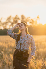 Girl with a retro photo camera in a golden rye field at sunset