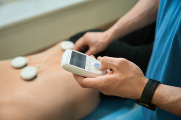 Physiotherapist performing electrical muscle stimulation on adult patient